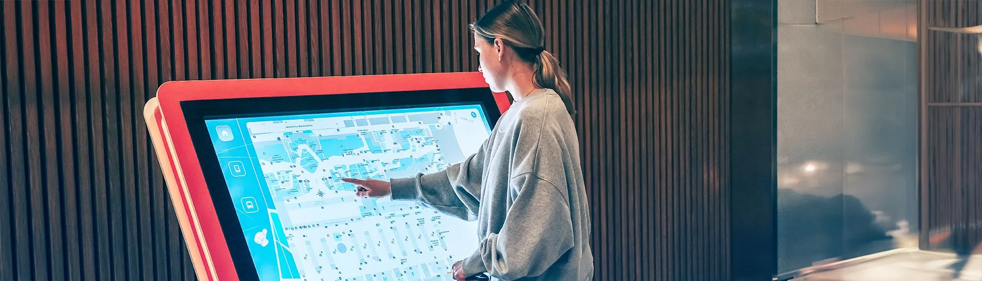 A shopper using an interactive touch directory to find a store in a shopping mall